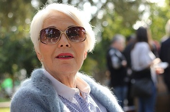 An older woman sits in the park wearing sunglasses to promote healthy vision